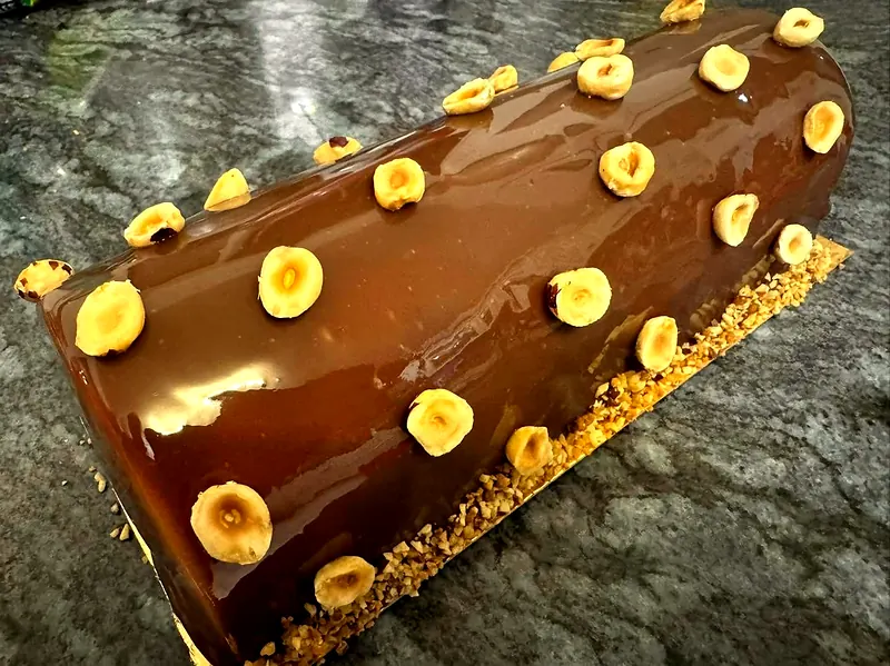 Bûche au glaçage chocolat au lait, noisettes entières et pied de noisettes concassées