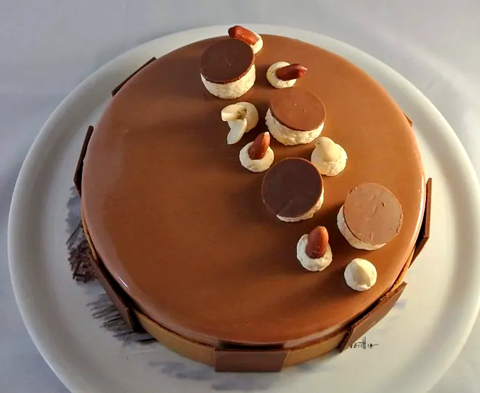 Entremets au glaçage lacté, décor de disques en chocolat et noisettes