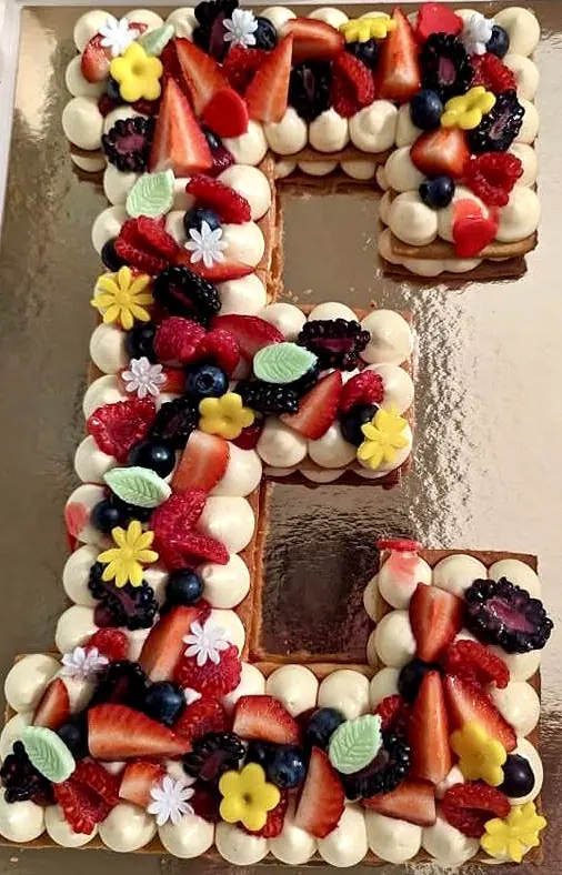 Letter cake en forme de E, crème, fruits rouges et fleurs